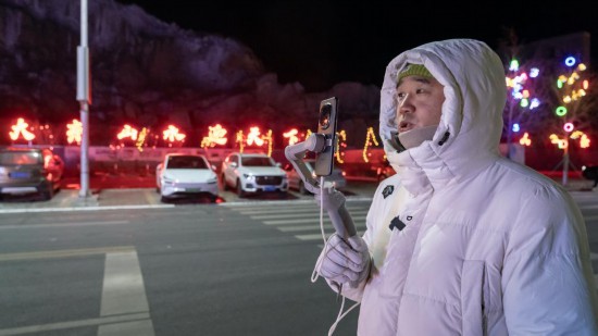 在吉林市阿什哈達霧凇觀景帶，霧凇播報員正在直播。新華社記者 李典 攝
