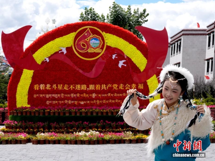 8月19日，隨著西藏自治區(qū)成立60周年慶?；顒优R近，拉薩氛圍濃。拉薩街頭，處處是張燈結(jié)彩的盛景，洋溢著一派祥和與歡騰的氛圍。圖為游客在拉薩大昭寺廣場上的大慶宣傳標(biāo)語前留念。<a target='_blank' href='/'>中新社</a>記者 李林 攝